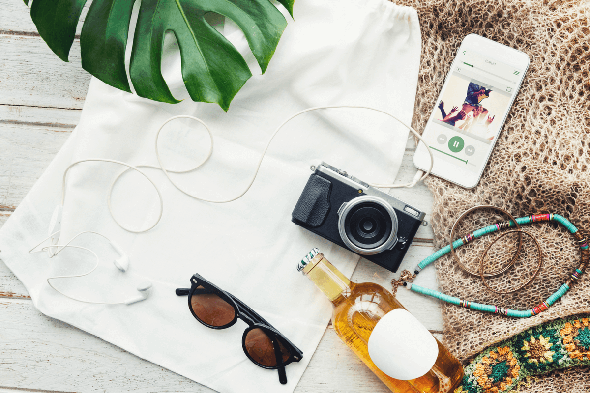 sunglasses, camera, headphones, and phone on a white towel